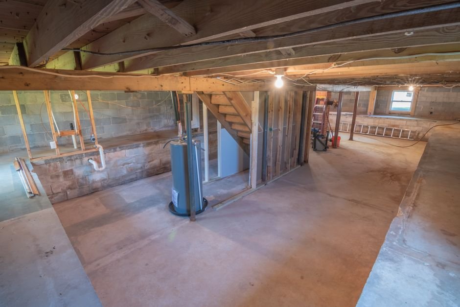 Unfinished residential basement with exposed plumbing and a water heater
