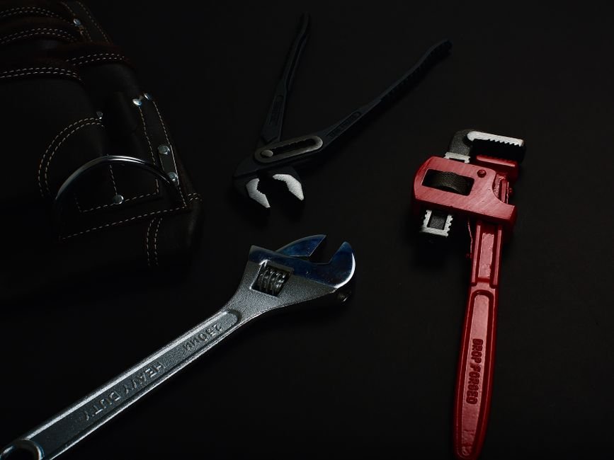 Wrenches and pliers laid out on a dark surface