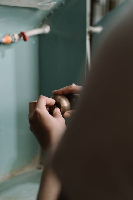 Plumber’s hands repairing a pipe under a kitchen sink