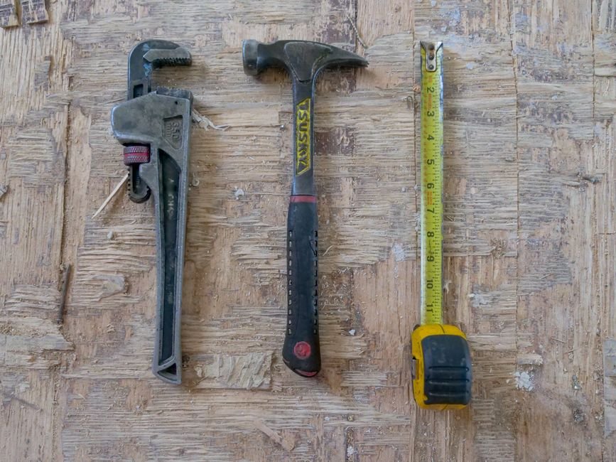 Pipe wrench, hammer, and measuring tape — plumbing repair tools